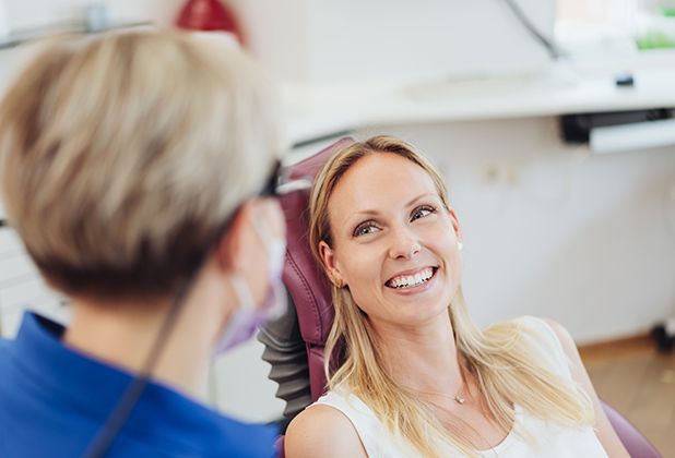 Relaxed dental patient smiling at her dentist