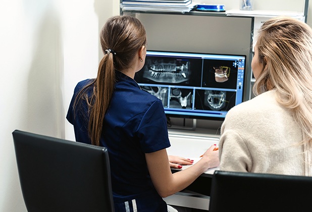 Dentist and dental patient looking at digital x-rays of teeth