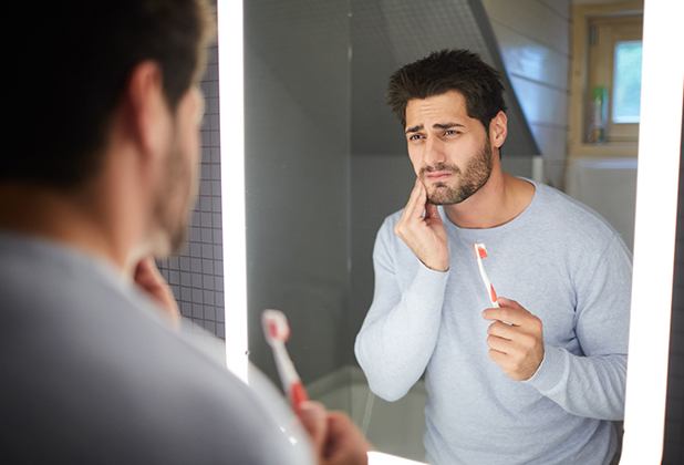 Man in need of emergency dentistry holding jaw in pain