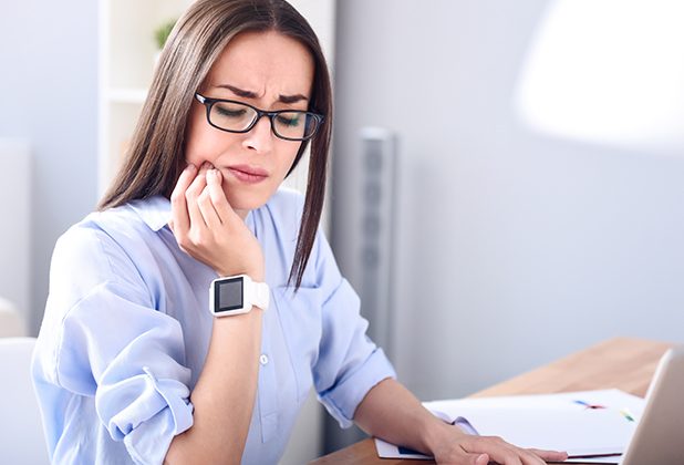 Woman in need of T M J therapy holding jaw