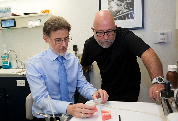 Dentist and dental patient looking at dental bridge options