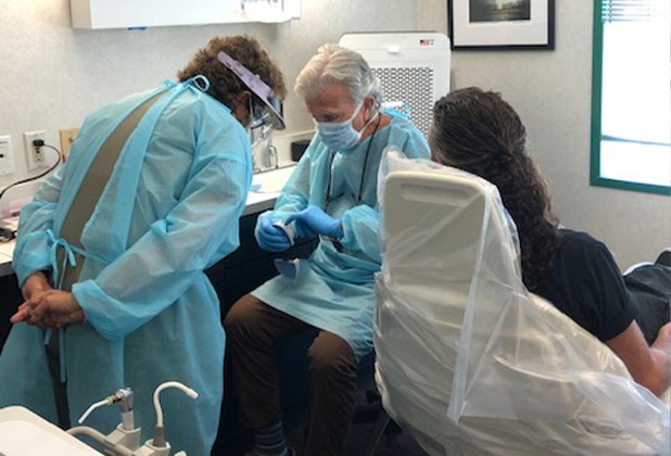 Dentist and team member examining smile model with dental patient